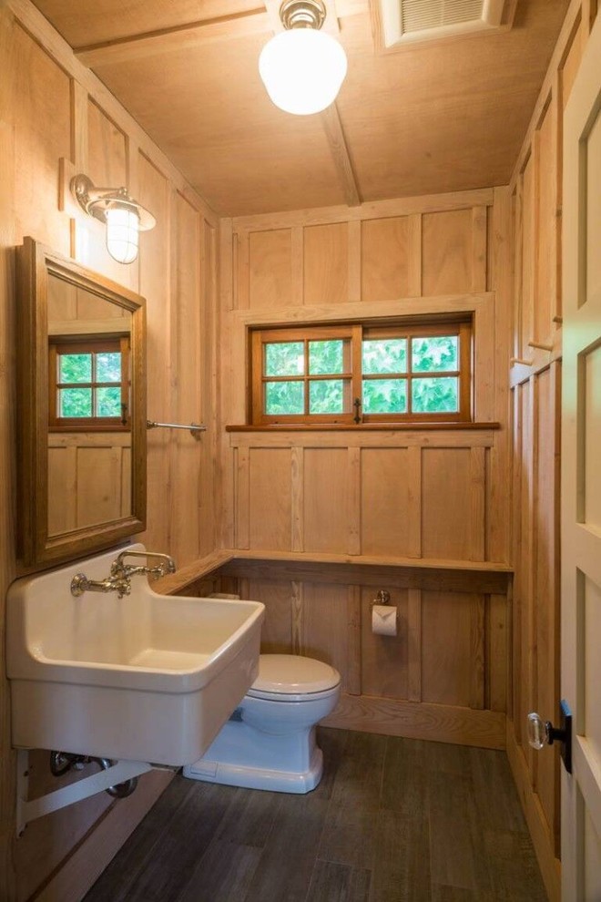 Immagine di un bagno di servizio country di medie dimensioni con piastrelle marroni, pareti marroni, pavimento in legno massello medio, lavabo sospeso e pavimento marrone