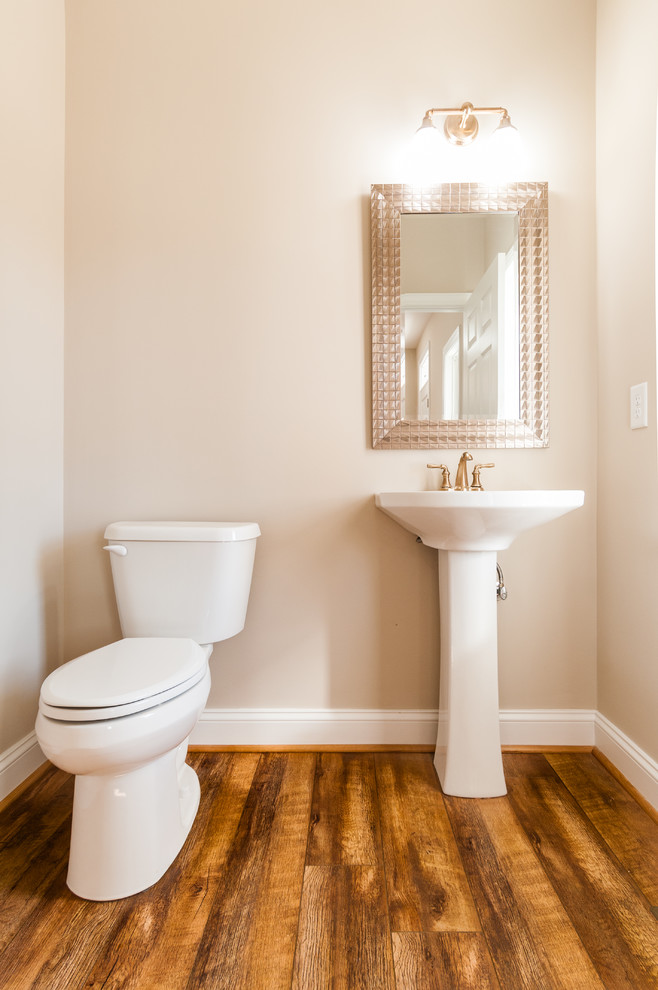 Kleine Rustikale Gästetoilette mit Wandtoilette mit Spülkasten, beiger Wandfarbe, dunklem Holzboden, Sockelwaschbecken und braunem Boden in Richmond
