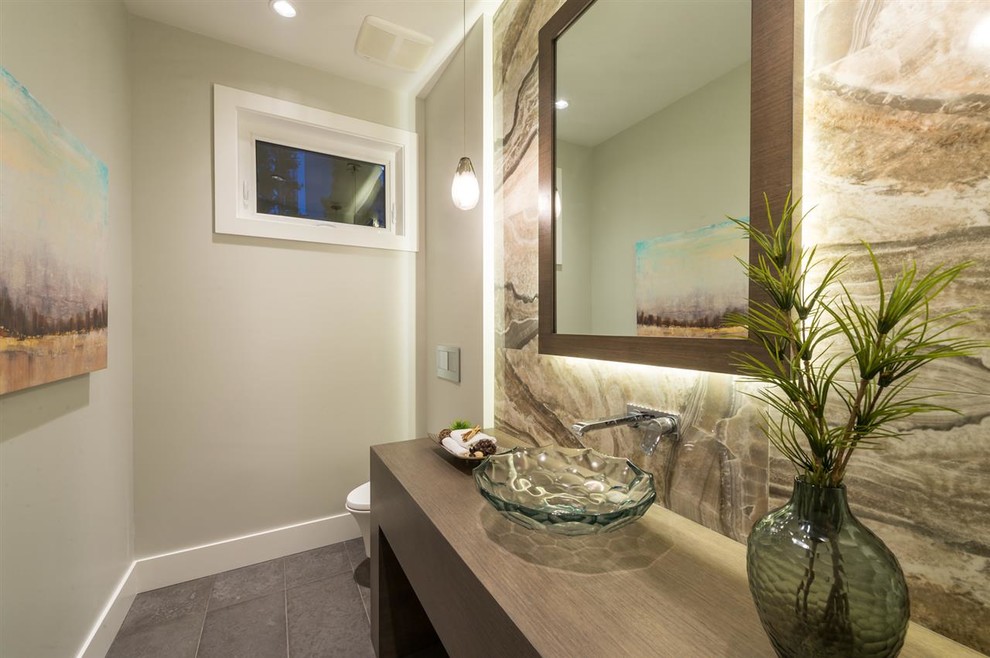Design ideas for a medium sized contemporary cloakroom in Vancouver with open cabinets, medium wood cabinets, a wall mounted toilet, grey tiles, stone slabs, grey walls, limestone flooring, a vessel sink and wooden worktops.