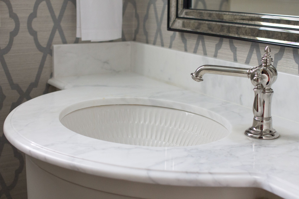 Aménagement d'un WC et toilettes classique avec un lavabo encastré, un placard en trompe-l'oeil, des portes de placard blanches et un plan de toilette en marbre.