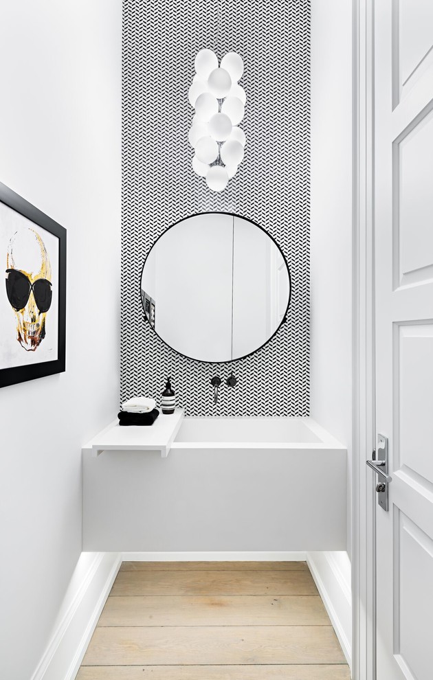 Moderne Gästetoilette mit schwarz-weißen Fliesen, weißer Wandfarbe, hellem Holzboden und Wandwaschbecken in Toronto