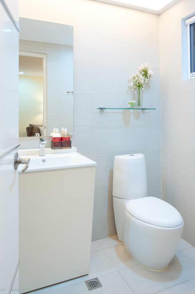 Moderne Gästetoilette mit integriertem Waschbecken, flächenbündigen Schrankfronten, beigen Schränken, Wandtoilette mit Spülkasten und grauen Fliesen in Sonstige