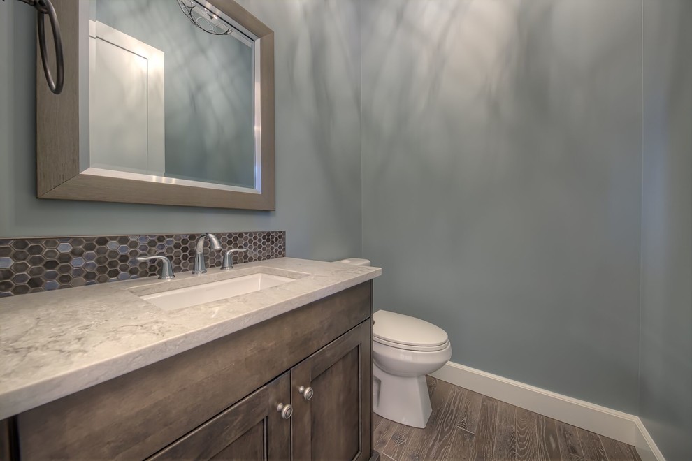 Urige Gästetoilette mit Schrankfronten im Shaker-Stil, Toilette mit Aufsatzspülkasten, farbigen Fliesen, Mosaikfliesen, braunem Holzboden, Unterbauwaschbecken, Quarzwerkstein-Waschtisch und grauem Boden in Calgary