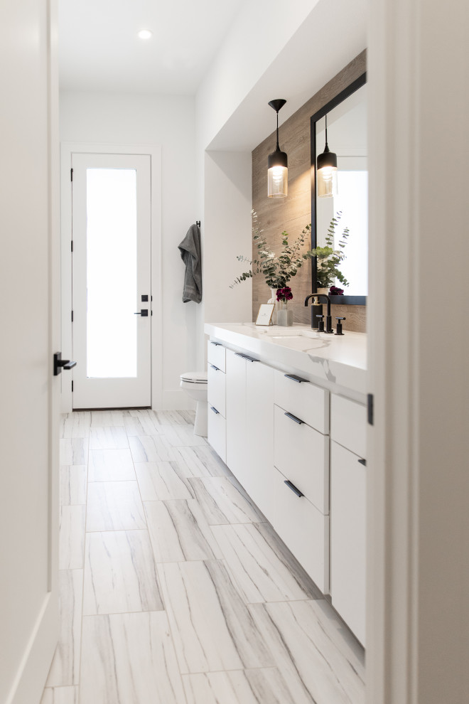 Photo of a medium sized modern cloakroom in Austin with white cabinets, a two-piece toilet, brown tiles, porcelain tiles, brown walls, ceramic flooring, a built-in sink, granite worktops, brown floors and white worktops.