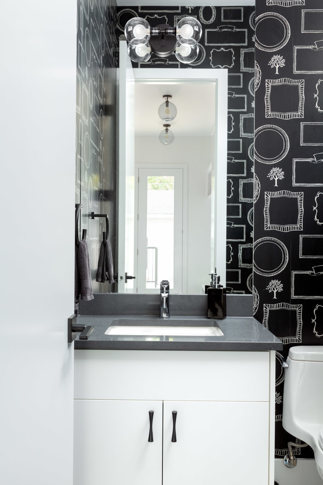 Inredning av ett klassiskt grå grått toalett, med släta luckor, vita skåp, svarta väggar och ett undermonterad handfat