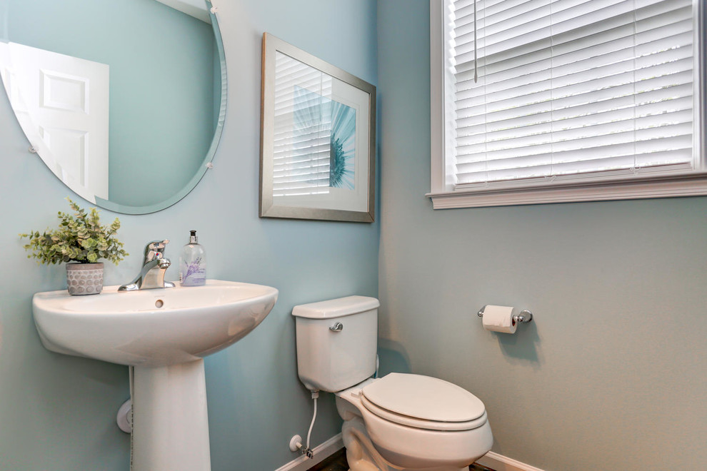 Ispirazione per un bagno di servizio design di medie dimensioni con WC a due pezzi, pareti blu, pavimento in legno massello medio, lavabo a colonna e pavimento marrone