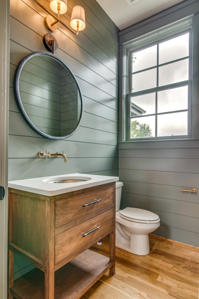 Inspiration for a mid-sized transitional light wood floor powder room remodel in Nashville with flat-panel cabinets, medium tone wood cabinets, a two-piece toilet, green walls, an undermount sink, quartz countertops and white countertops