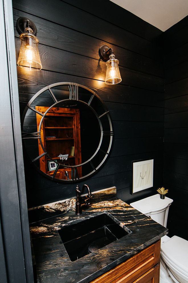 Idée de décoration pour un petit WC et toilettes champêtre avec un placard à porte shaker, des portes de placard marrons, WC à poser, un mur noir, carreaux de ciment au sol, un lavabo posé, un plan de toilette en granite et un plan de toilette noir.