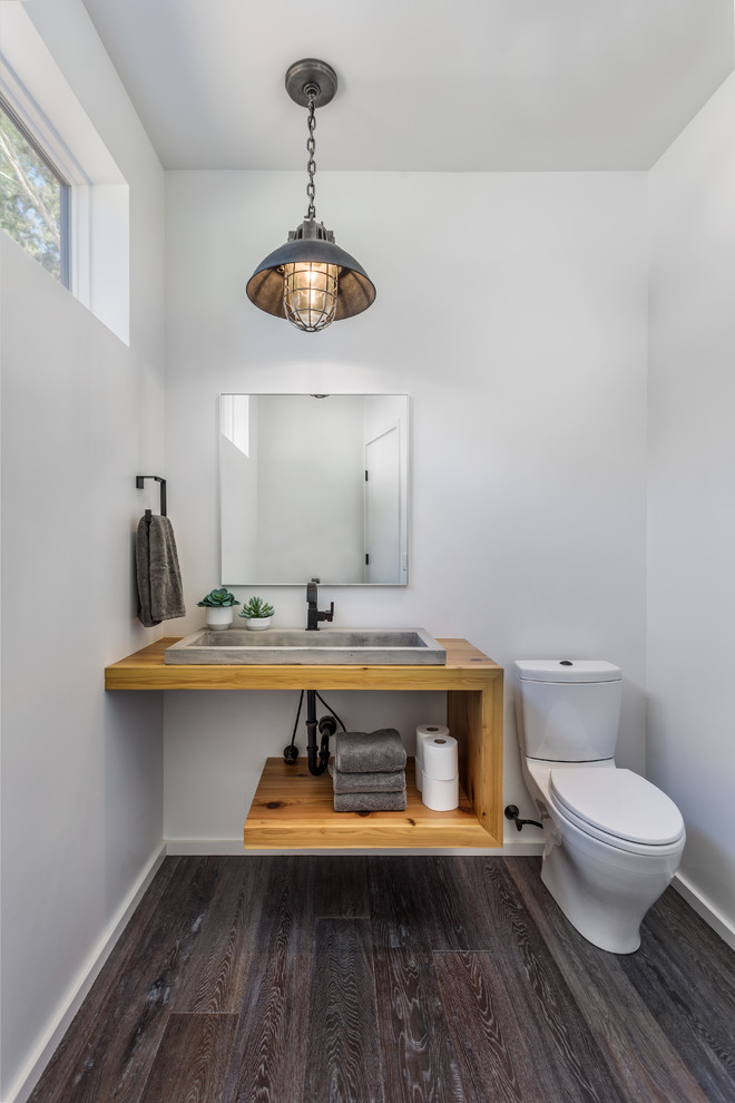 Inspiration for a contemporary cloakroom in Charleston with open cabinets, medium wood cabinets, a two-piece toilet, white walls, dark hardwood flooring, a trough sink, wooden worktops and brown worktops.