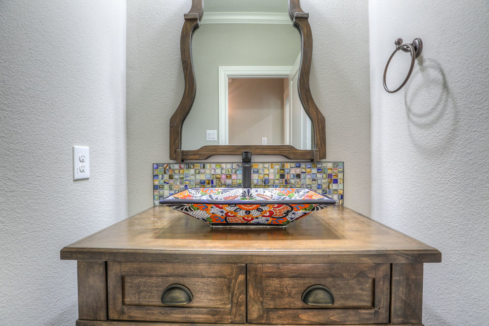 Small mediterranean cloakroom in Houston with shaker cabinets, dark wood cabinets, a two-piece toilet, multi-coloured tiles, mosaic tiles, beige walls, dark hardwood flooring, a vessel sink, wooden worktops and brown floors.