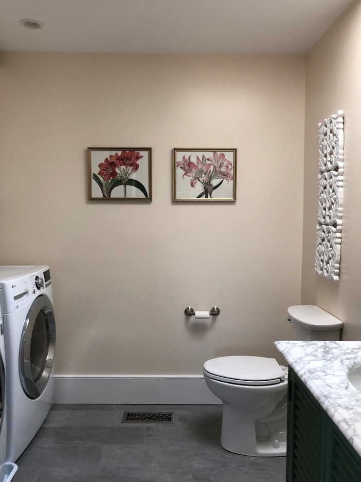 Inredning av ett lantligt mellanstort vit vitt toalett, med luckor med lamellpanel, gröna skåp, en toalettstol med separat cisternkåpa, vita väggar, klinkergolv i keramik, ett undermonterad handfat, marmorbänkskiva och grått golv