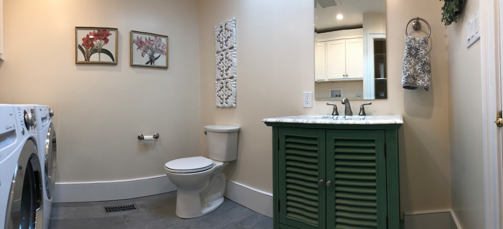 This is an example of a medium sized farmhouse cloakroom in Philadelphia with louvered cabinets, green cabinets, a two-piece toilet, white walls, ceramic flooring, a submerged sink, marble worktops, grey floors and white worktops.