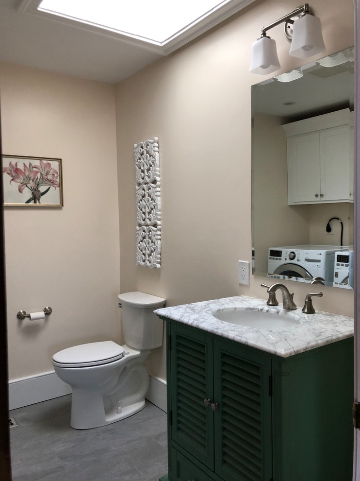 This is an example of a medium sized country cloakroom in Philadelphia with louvered cabinets, green cabinets, a two-piece toilet, white walls, ceramic flooring, a submerged sink, marble worktops, grey floors and white worktops.