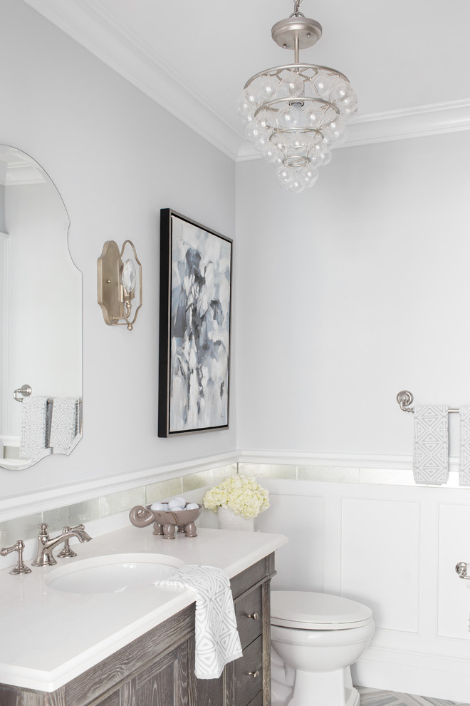Immagine di un bagno di servizio stile marinaro con ante in legno chiaro, pareti grigie, lavabo sottopiano e top bianco