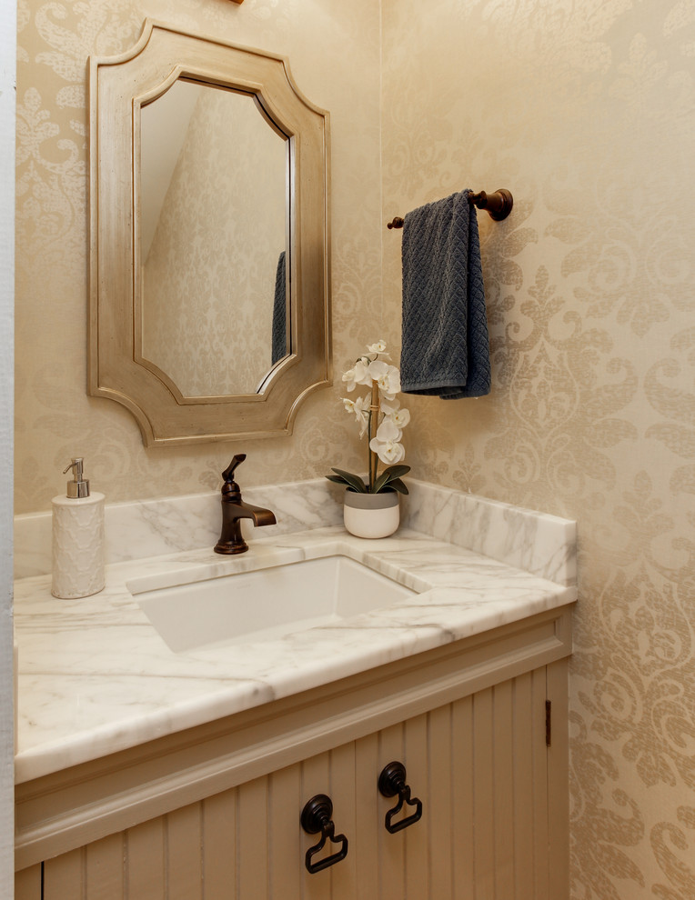 Ispirazione per un piccolo bagno di servizio classico con ante beige, WC a due pezzi, pareti beige, pavimento in legno massello medio, lavabo sottopiano, top in marmo e pavimento marrone