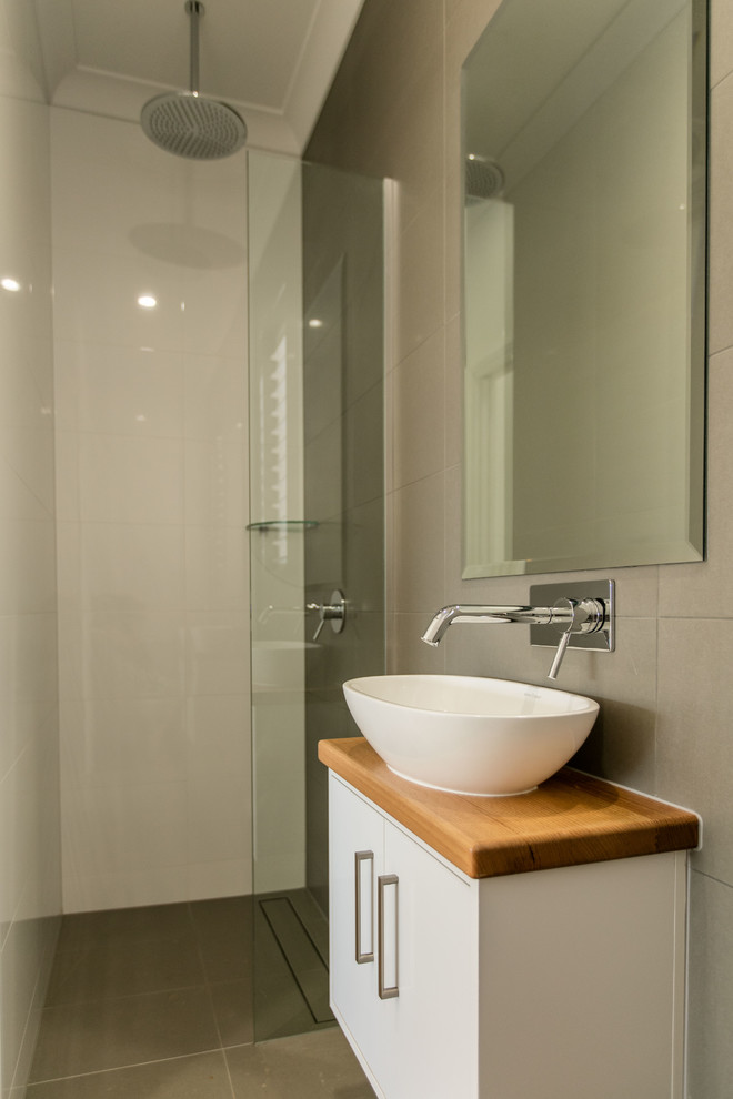 Kleine Moderne Gästetoilette mit Waschtisch aus Holz, grauen Fliesen, Keramikfliesen, flächenbündigen Schrankfronten und weißen Schränken in Cairns