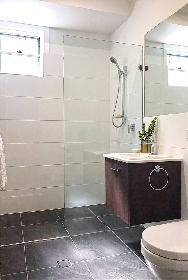 This is an example of a large modern bathroom in Brisbane with dark wood cabinets, a one-piece toilet, white tiles, ceramic tiles, white walls, ceramic flooring, a built-in sink, engineered stone worktops, grey floors and white worktops.