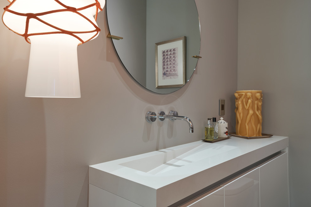 Medium sized modern cloakroom in Los Angeles with flat-panel cabinets, white cabinets, a one-piece toilet, beige walls, light hardwood flooring, an integrated sink, engineered stone worktops, yellow floors and white worktops.