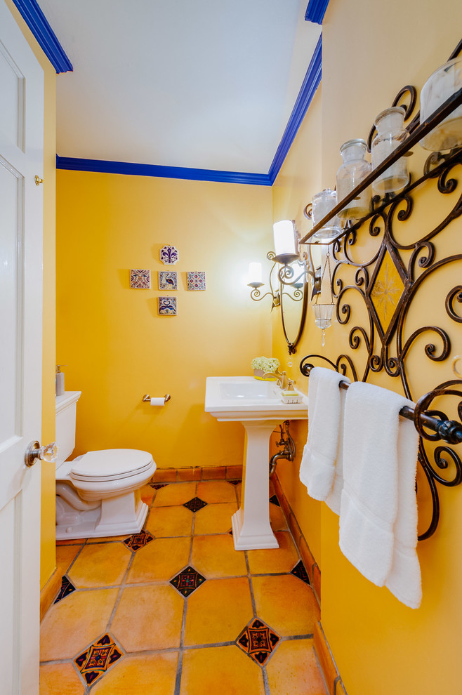 Foto på ett litet medelhavsstil toalett, med en toalettstol med separat cisternkåpa, gula väggar, ett piedestal handfat och gult golv