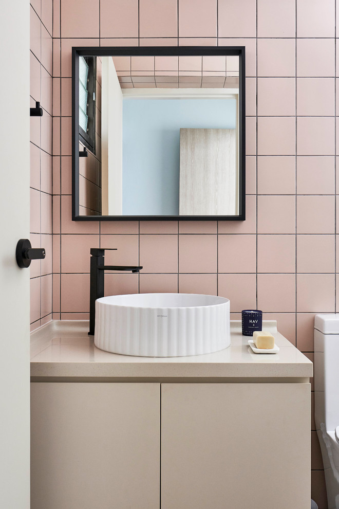 Photo of a contemporary cloakroom in Singapore with flat-panel cabinets, beige cabinets, pink tiles, pink walls, a vessel sink and beige worktops.