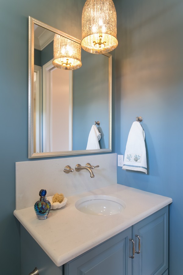 Klassische Gästetoilette mit Unterbauwaschbecken, profilierten Schrankfronten, blauen Schränken, Quarzwerkstein-Waschtisch, Wandtoilette mit Spülkasten, beigen Fliesen und blauer Wandfarbe in Miami