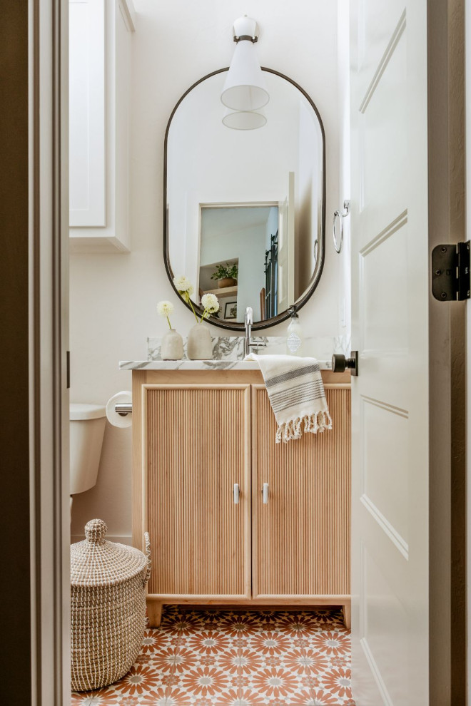 Example of a mid-sized transitional white tile and porcelain tile cement tile floor and orange floor powder room design in Oklahoma City with furniture-like cabinets, light wood cabinets, a one-piece toilet, white walls, an undermount sink, marble countertops, white countertops and a built-in vanity