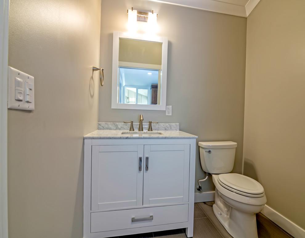Immagine di un piccolo bagno di servizio design con lavabo sottopiano, ante in stile shaker, ante bianche, top in granito, WC a due pezzi, pareti beige, pavimento in gres porcellanato e piastrelle marroni