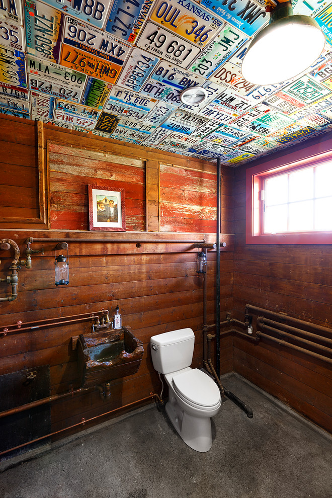 Foto på ett mellanstort lantligt toalett, med möbel-liknande, skåp i mörkt trä, betonggolv, ett väggmonterat handfat och grått golv