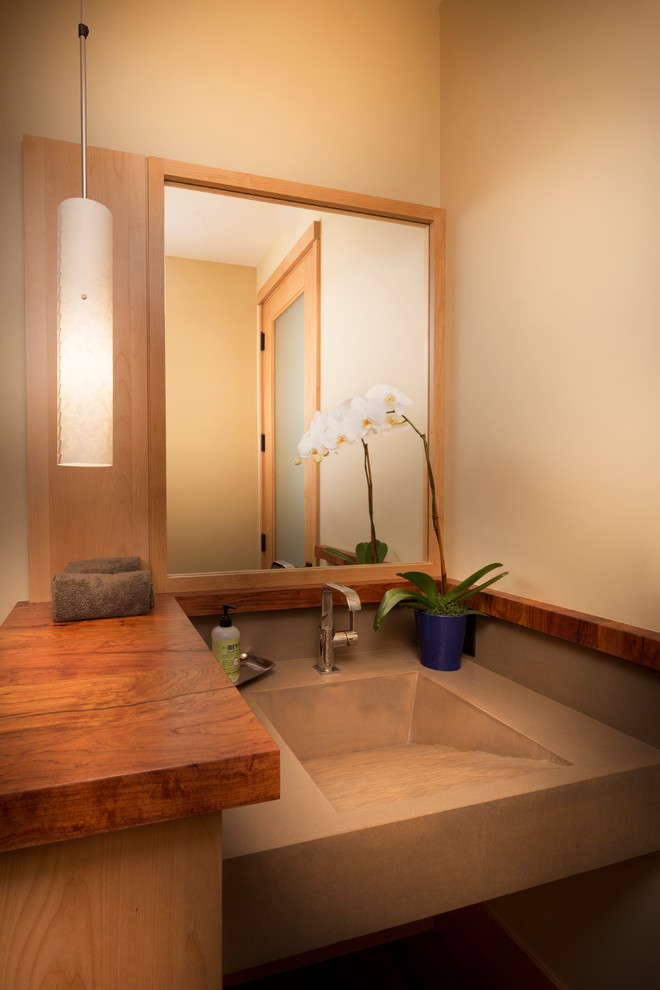 Réalisation d'un WC et toilettes chalet en bois clair de taille moyenne avec un lavabo intégré, un placard en trompe-l'oeil, un plan de toilette en béton et un mur beige.