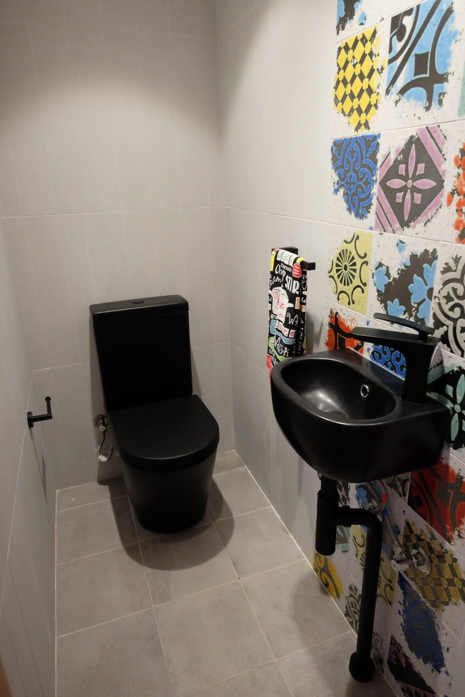 На фото: маленький туалет в современном стиле с раздельным унитазом, разноцветной плиткой, керамогранитной плиткой, подвесной раковиной, серыми стенами, серым полом и черной столешницей для на участке и в саду