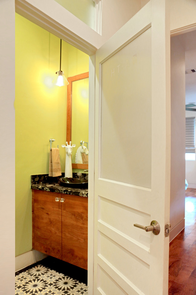This is an example of a cloakroom in Houston with medium wood cabinets, yellow walls, ceramic flooring, a vessel sink, granite worktops, multi-coloured floors, black worktops and flat-panel cabinets.