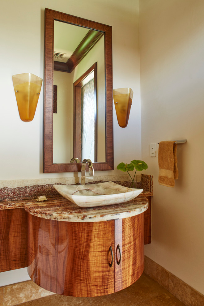 Foto på ett stort tropiskt toalett, med möbel-liknande, skåp i mörkt trä, granitbänkskiva, stenhäll, flerfärgade väggar, travertin golv och ett fristående handfat