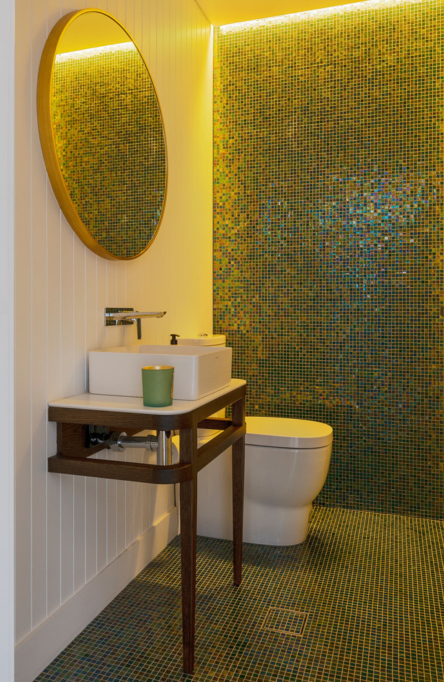 На фото: большой туалет в современном стиле с открытыми фасадами, унитазом-моноблоком, разноцветной плиткой, плиткой мозаикой, разноцветными стенами, полом из мозаичной плитки, раковиной с несколькими смесителями, столешницей из искусственного камня и белым полом