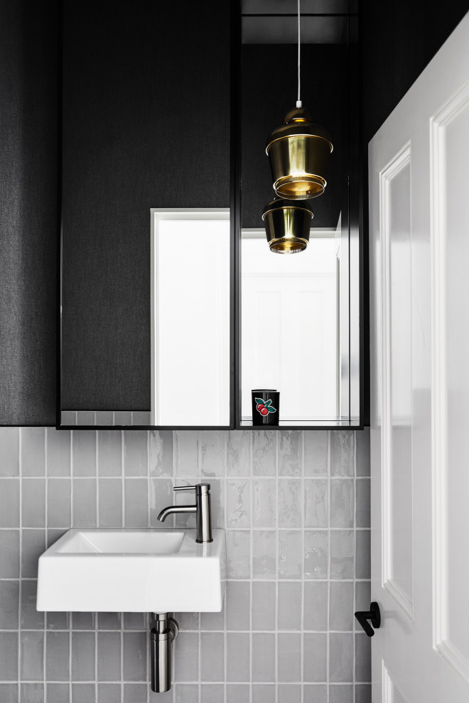 На фото: туалет в современном стиле с серой плиткой, черными стенами и подвесной раковиной с