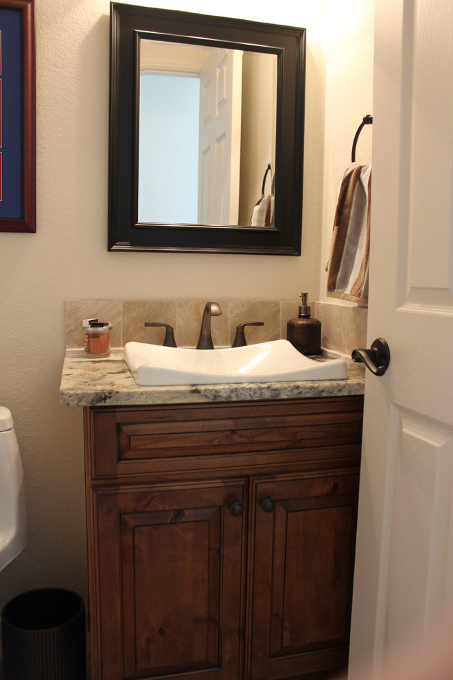Idée de décoration pour un WC et toilettes sud-ouest américain en bois brun avec un placard avec porte à panneau surélevé, un sol en marbre, une vasque et un plan de toilette en granite.