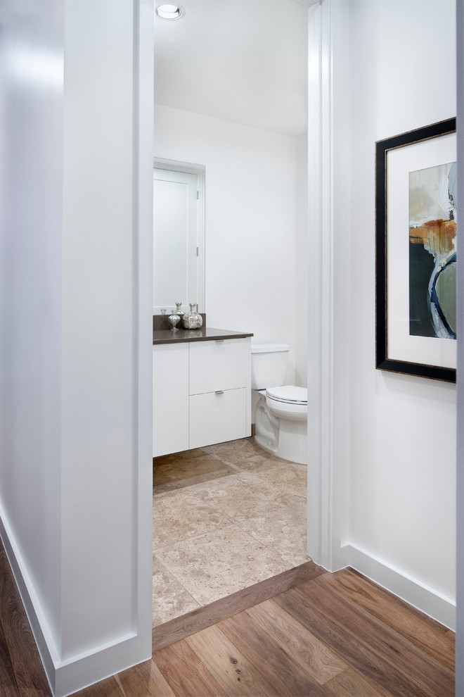 Small contemporary cloakroom in Austin with flat-panel cabinets, white cabinets, a two-piece toilet, white walls, travertine flooring, a submerged sink, solid surface worktops and beige floors.