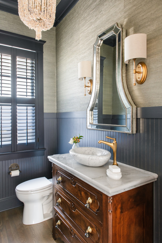 Moderne Gästetoilette mit blauer Wandfarbe, braunem Holzboden, vertäfelten Wänden, verzierten Schränken, braunen Schränken, Marmor-Waschbecken/Waschtisch und freistehendem Waschtisch in Charleston