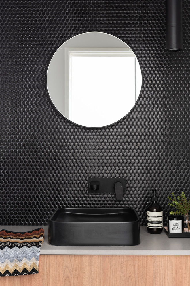 На фото: туалет в стиле лофт с фасадами цвета дерева среднего тона, черной плиткой, плиткой мозаикой, полом из цементной плитки, настольной раковиной, столешницей из искусственного кварца, черным полом и серой столешницей