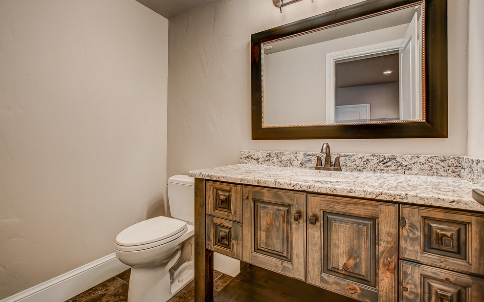 Medium sized traditional cloakroom in Denver with raised-panel cabinets, medium wood cabinets, a two-piece toilet, beige tiles, stone tiles, beige walls, porcelain flooring, a submerged sink and granite worktops.