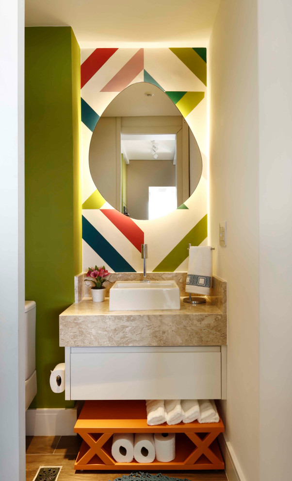 Cette image montre un WC et toilettes design avec un placard à porte plane, des portes de placard blanches, un carrelage multicolore, un mur vert, une vasque, un sol marron, un plan de toilette beige et meuble-lavabo suspendu.