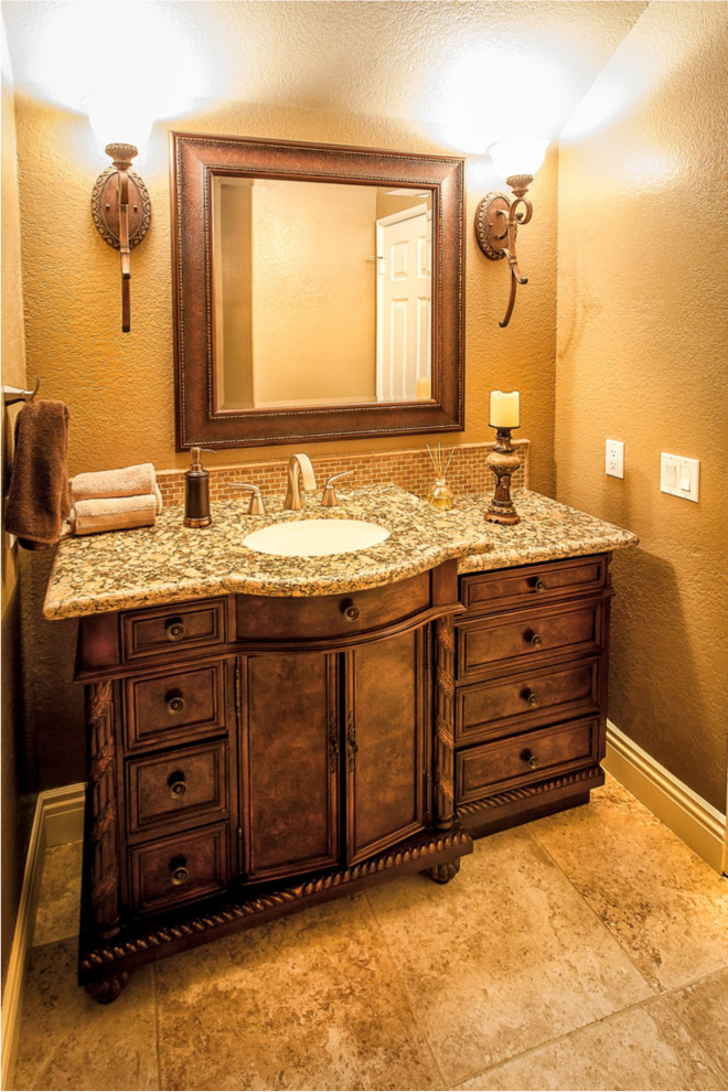 Small tuscan beige tile powder room photo in Orange County with granite countertops, brown walls, dark wood cabinets, an undermount sink and furniture-like cabinets