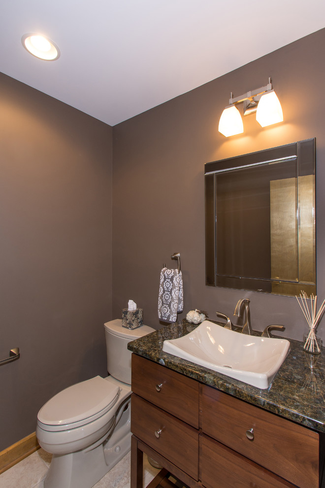 Example of a mid-sized eclectic beige tile porcelain tile powder room design in Columbus with a drop-in sink, furniture-like cabinets, dark wood cabinets, granite countertops, a two-piece toilet and brown walls