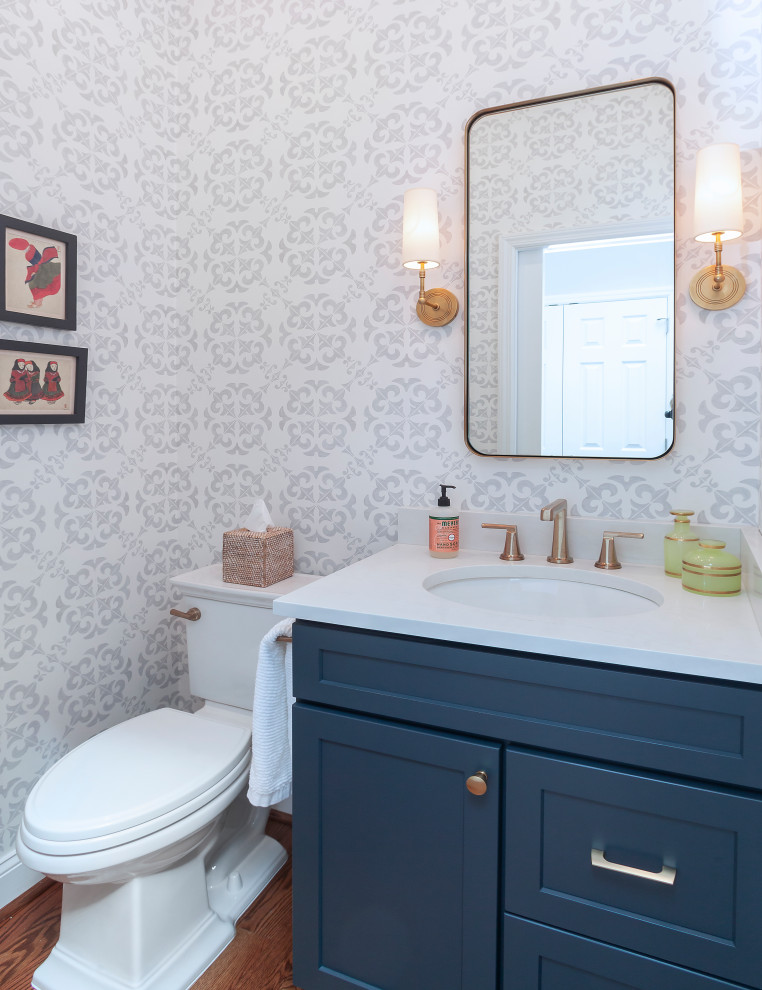 Inspiration for a small transitional medium tone wood floor and brown floor powder room remodel in Philadelphia with shaker cabinets, blue cabinets, gray walls, a console sink, quartzite countertops and white countertops