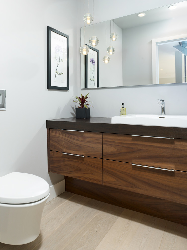 Cette photo montre un petit WC suspendu tendance en bois brun avec un placard à porte plane, un mur gris, parquet clair, un lavabo posé, un plan de toilette en quartz modifié, un sol beige et un plan de toilette noir.