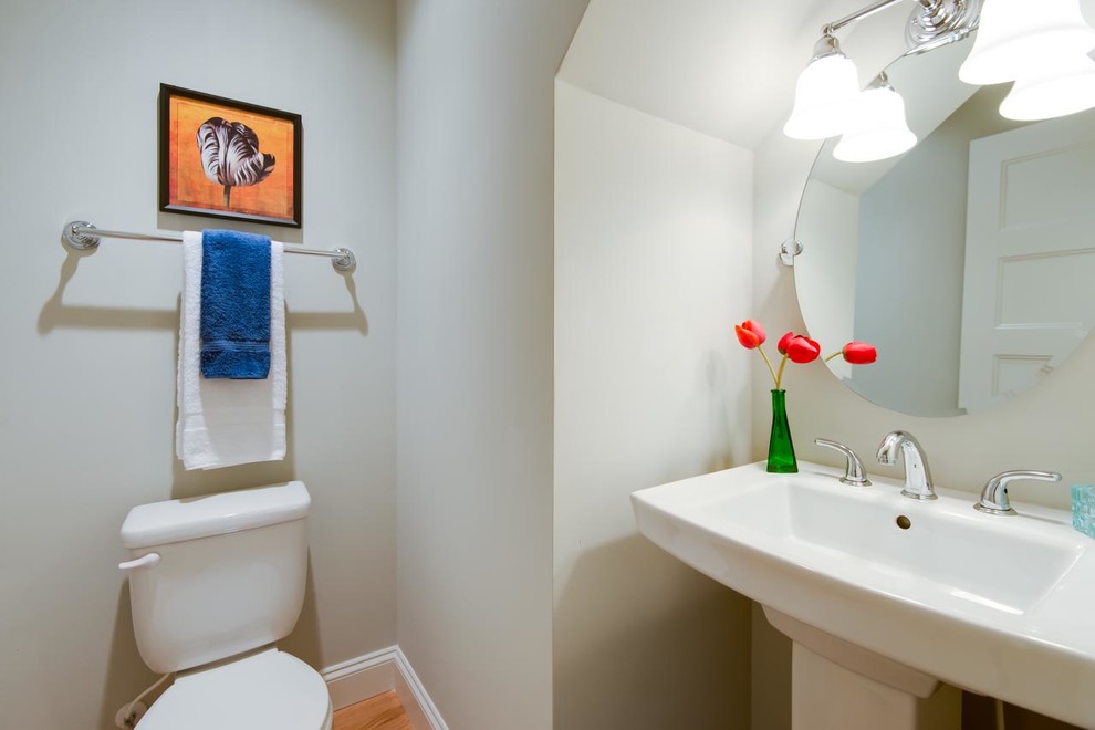 Idee per un piccolo bagno di servizio chic con WC a due pezzi, pareti beige, pavimento in legno massello medio, lavabo a colonna e pavimento marrone