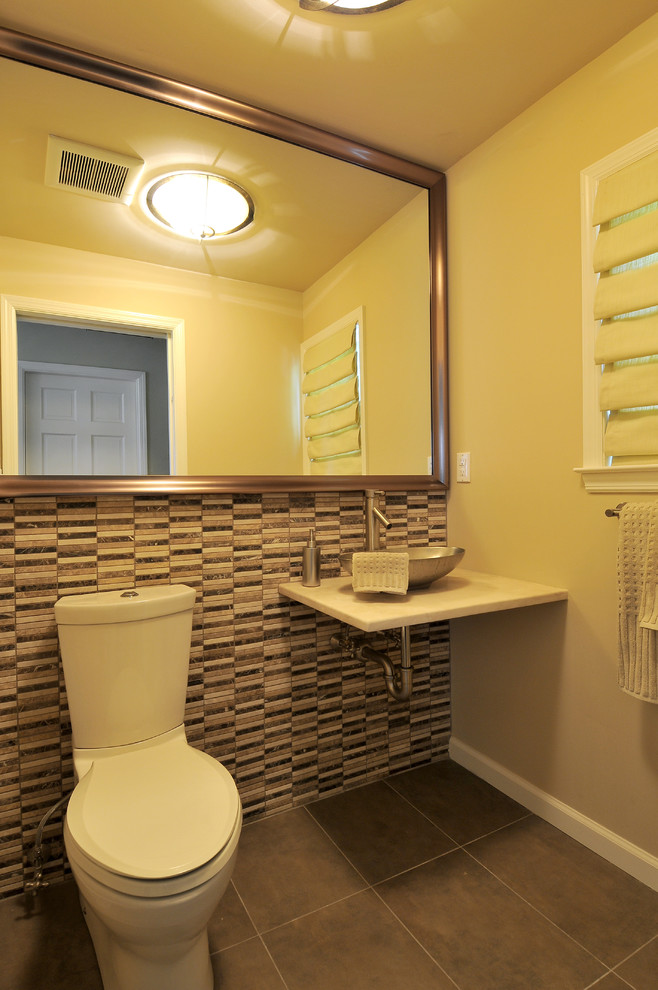 Photo of a medium sized contemporary cloakroom in New York with a two-piece toilet, multi-coloured tiles, porcelain tiles, beige walls, porcelain flooring, a vessel sink and brown floors.
