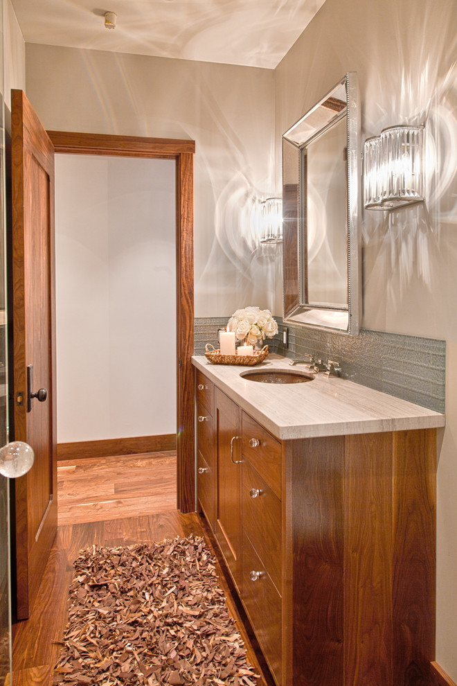 Immagine di un bagno di servizio chic con lavabo sottopiano, ante in stile shaker, ante in legno scuro, WC monopezzo, piastrelle di vetro e pareti grigie