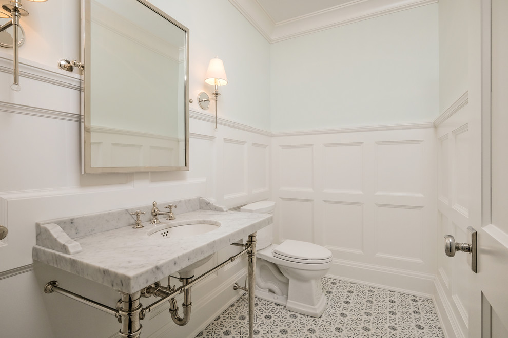 This is an example of an expansive traditional cloakroom in New York with open cabinets, a two-piece toilet, blue walls, marble flooring, a submerged sink, marble worktops, white floors and white worktops.