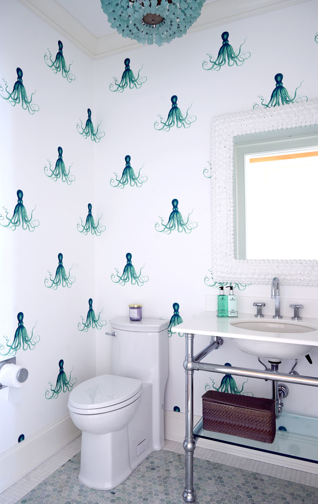 Bild på ett mellanstort maritimt vit vitt toalett, med en toalettstol med hel cisternkåpa, vita väggar, mosaikgolv, ett undermonterad handfat, bänkskiva i akrylsten och blått golv