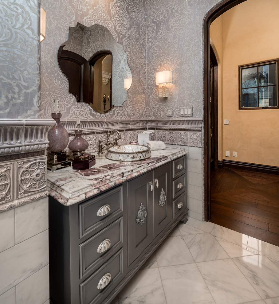 Photo of a large modern cloakroom in Phoenix with raised-panel cabinets, grey cabinets, a two-piece toilet, multi-coloured tiles, ceramic tiles, multi-coloured walls, marble flooring, a built-in sink, marble worktops, beige floors and yellow worktops.